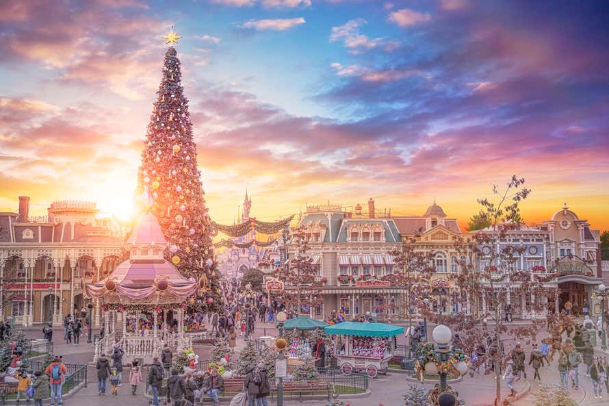 Árvore de Natal gigante iluminada à noite na praça principal da Disneyland® Paris
