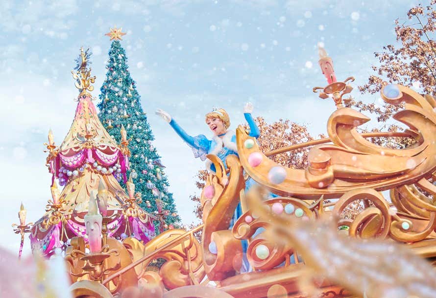 A Cinderela acenando de um carro alegórico dourado durante o desfile natalino com neve