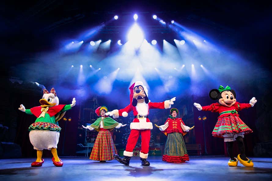 Personagens Disney com trajes tradicionais se apresentando no show musical natalino