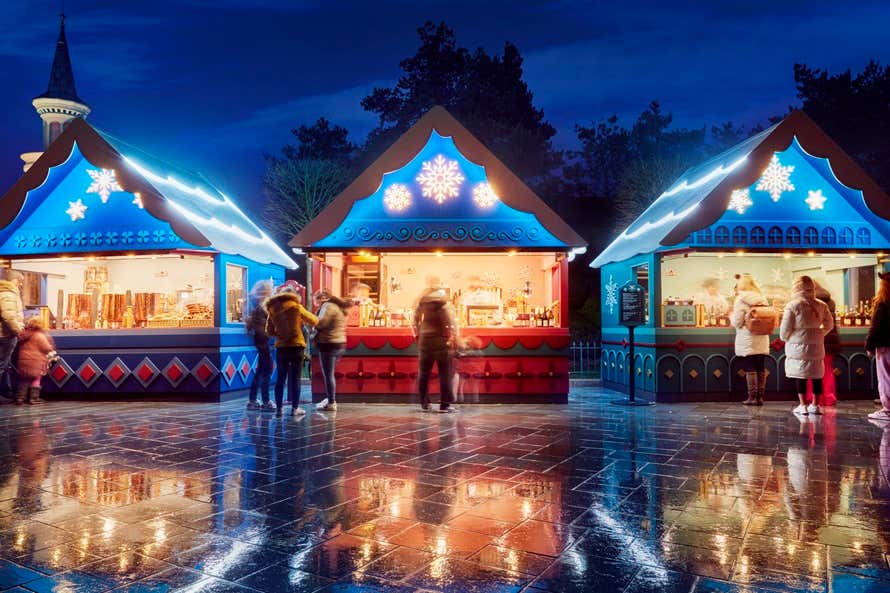 Mercado natalino com barracas de madeira iluminadas e estandes de comida da estação