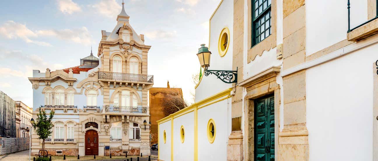 Palacete Belmarço de fachada azul y piedra junto a edificio blanco con detalles amarillos en el centro histórico de Faro