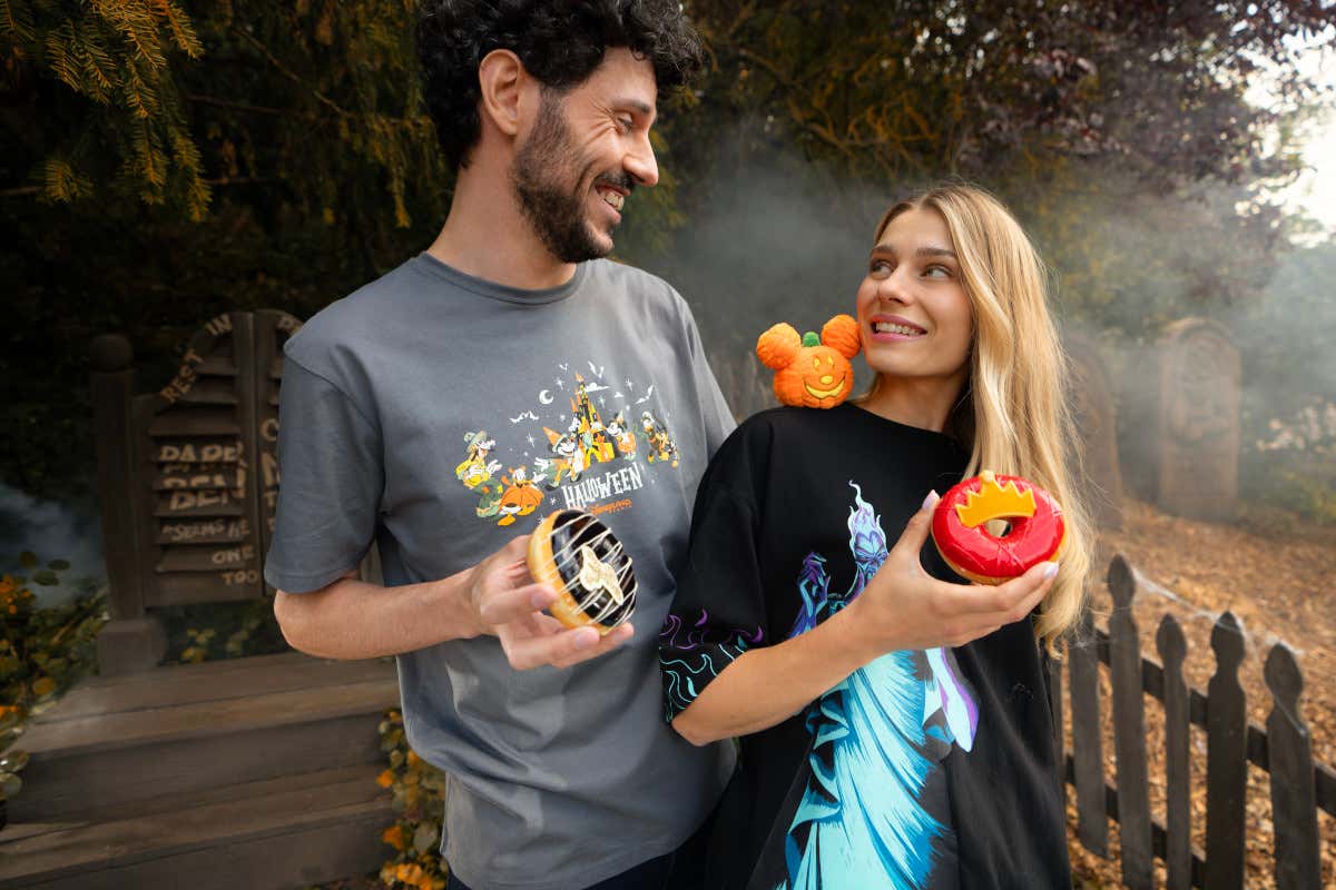 Un hombre y una mujer en el parque Disneyland París tomando unos donuts con temática de Halloween