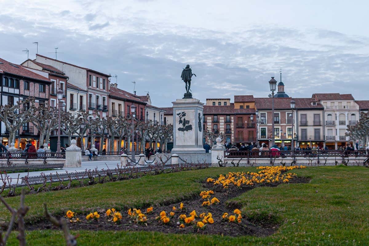 Estatua de Cervantes en la plaza de Alcalá de Henares con parterre de flores amarillas
