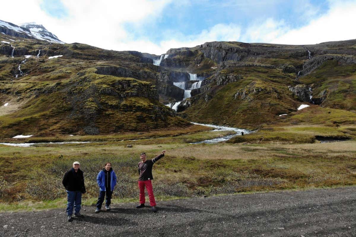 Tres personas en la cascada Klifbrekkufossar, en la región de los Fiordos del Este de Islandia.