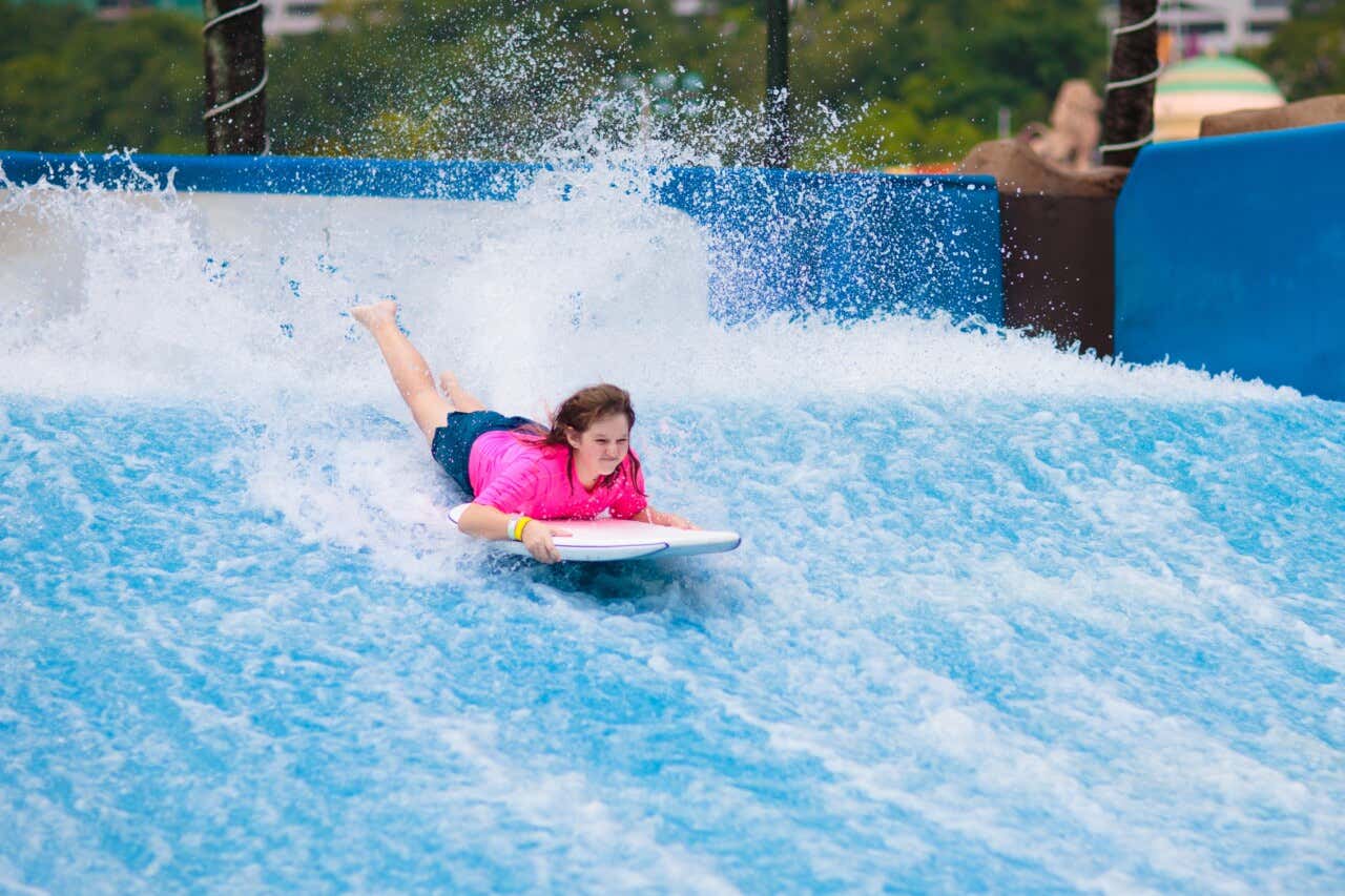 Uma menina praticando flowrider deitada, no estilo bodyboard