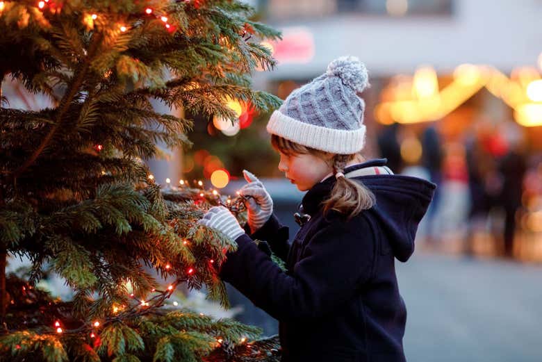 Una niña observa los adornos navideños del árbol