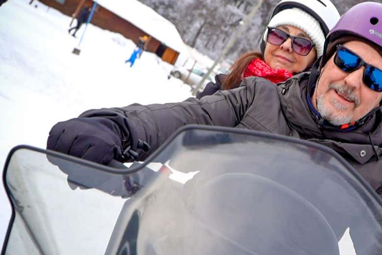 Una pareja subida a la moto de nieve