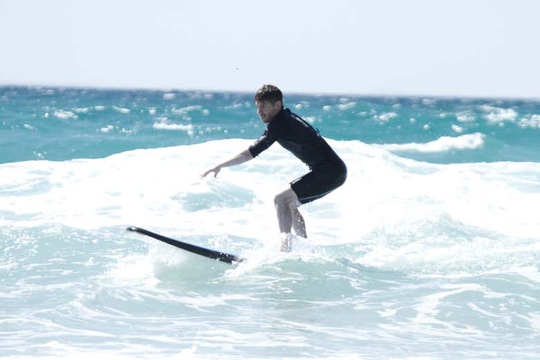 A surfer rides a small wave, keeping steady as he glides across 
