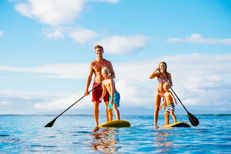 A family enjoys stand-up paddleboarding together on calm, clear 