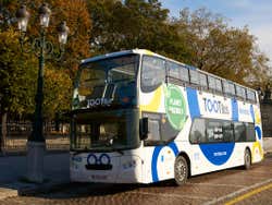 A doube decker bus parked along a curb, empty of passengers