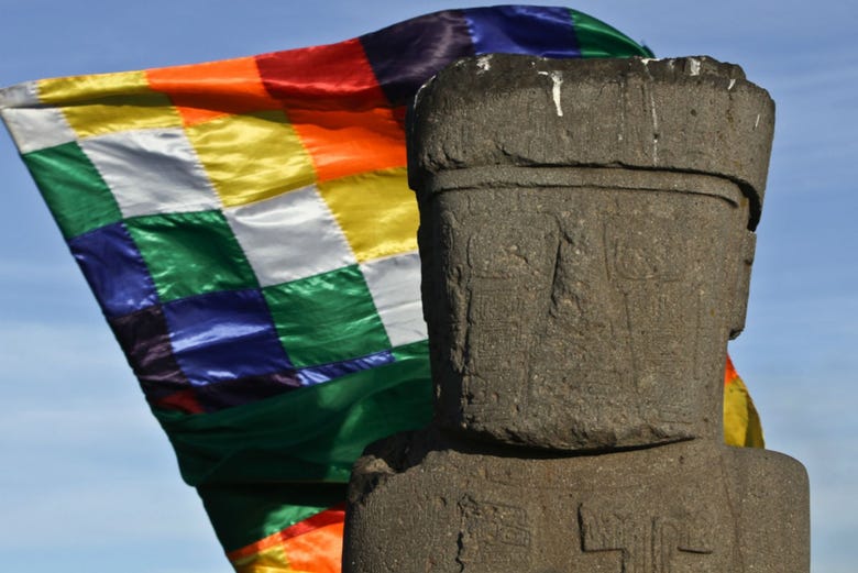 Estátua Tiwanaku com a bandeira Wiphala ao fundo