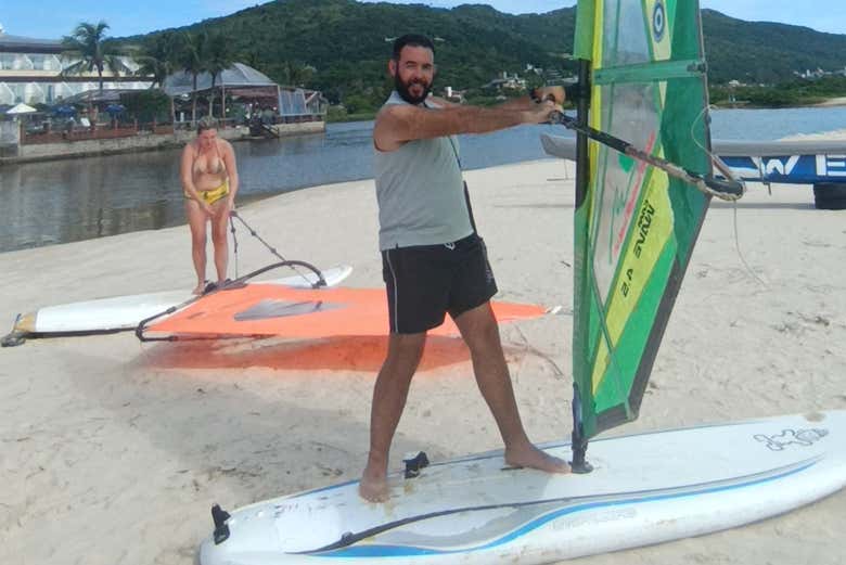 Levantando uma vela de windsurf na praia