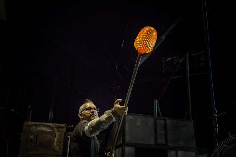 Um trabalhador criando uma peça de vidro