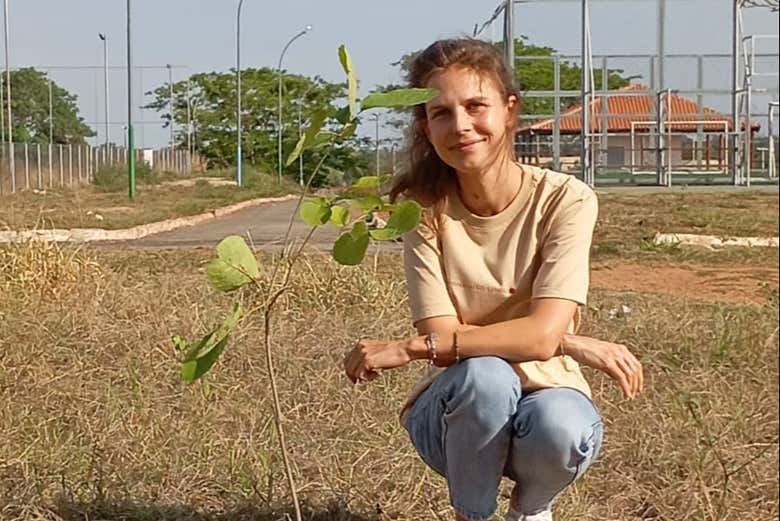 Posando junto al árbol que acaba de plantar