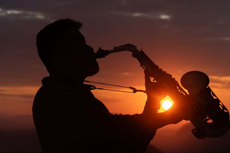 Tocando saxofone sob o sol do amanhecer