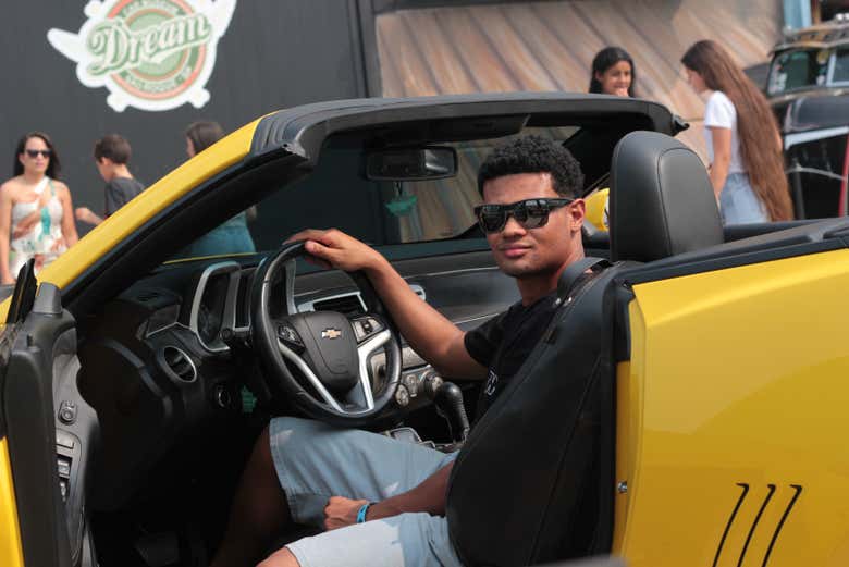 Un chico subido a un Porsche amarillo