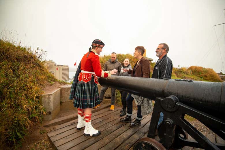 Turistas con un soldado canadiense mostrándoles un cañón