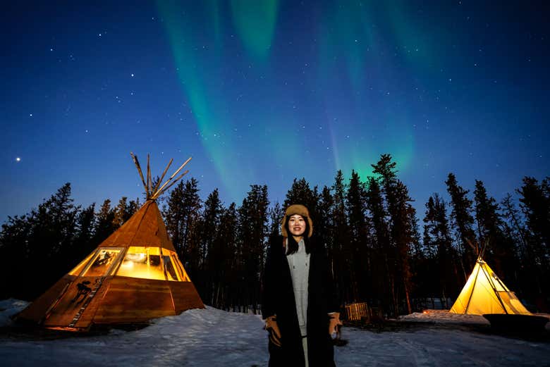 Disfrutando de la aurora boreal junto a unas cabañas