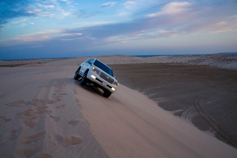 Vehículo todoterreno en las dunas al atardecer