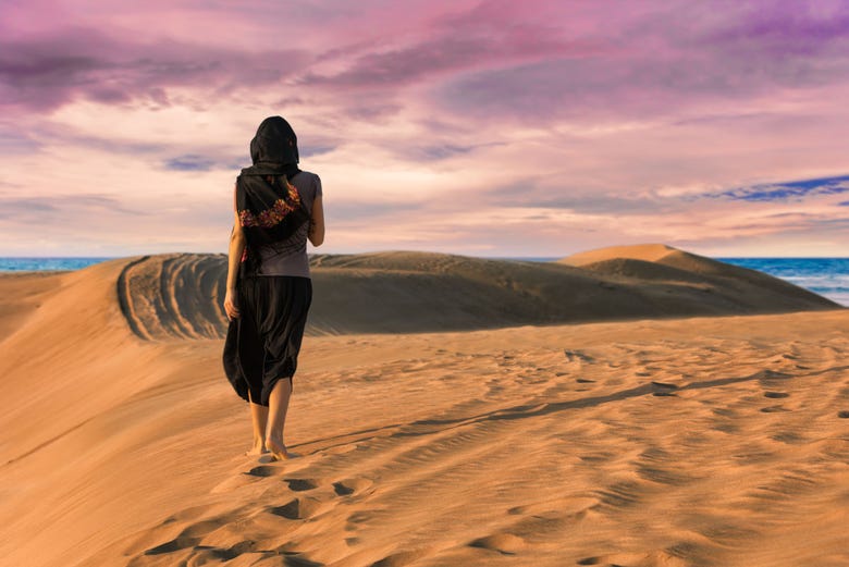 Mujer caminando por el desierto al atardecer