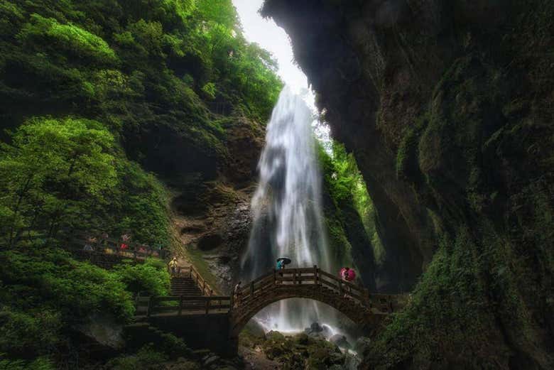 Un puente de madera con una cascada de fondo
