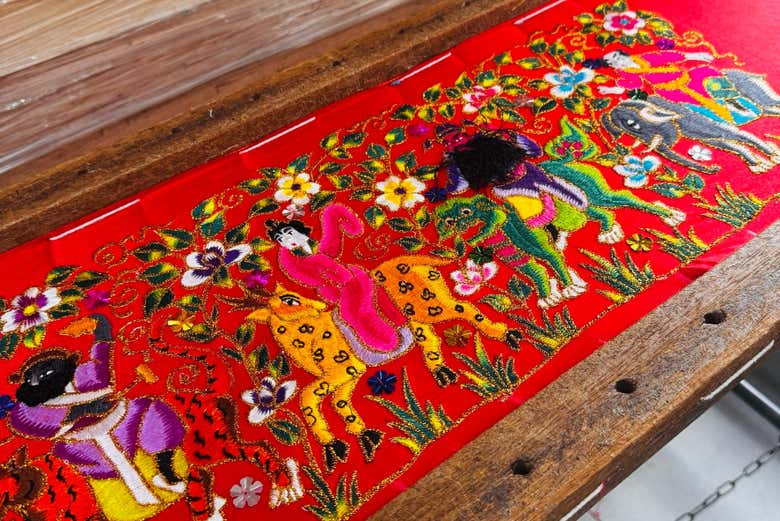 Textil bordado con figuras de animales y flores,