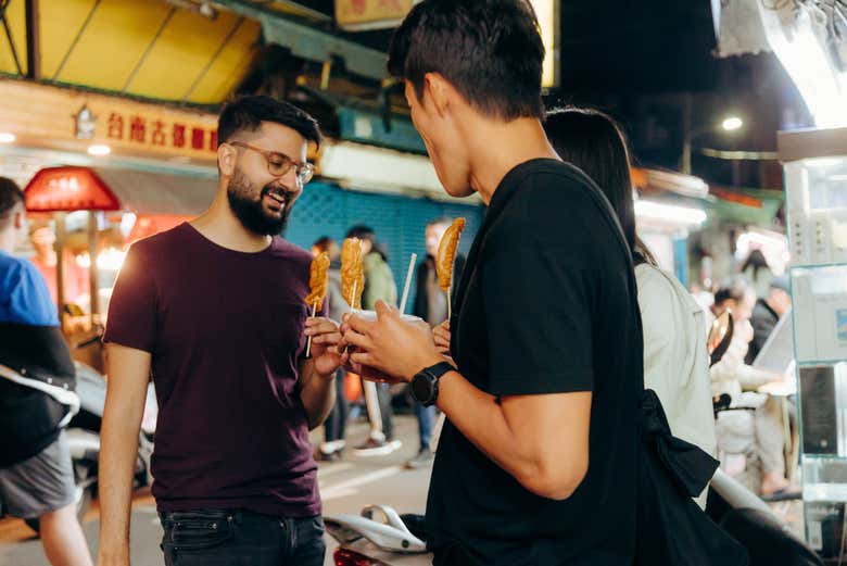 Probando unas brochetas en un puesto callejero nocturno