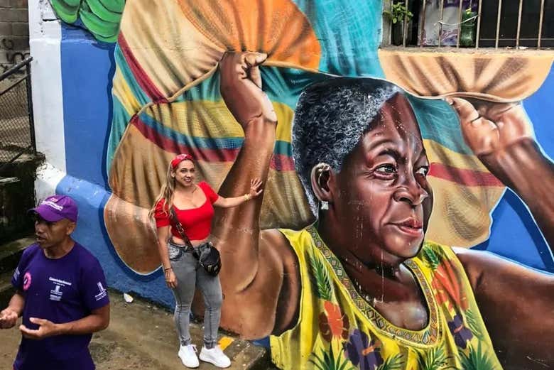 Una joven junto al mural 'La vida al hombro' en Medellín