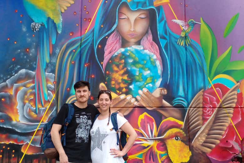 Una pareja joven junto al mural 'Madre naturaleza' en Medellín