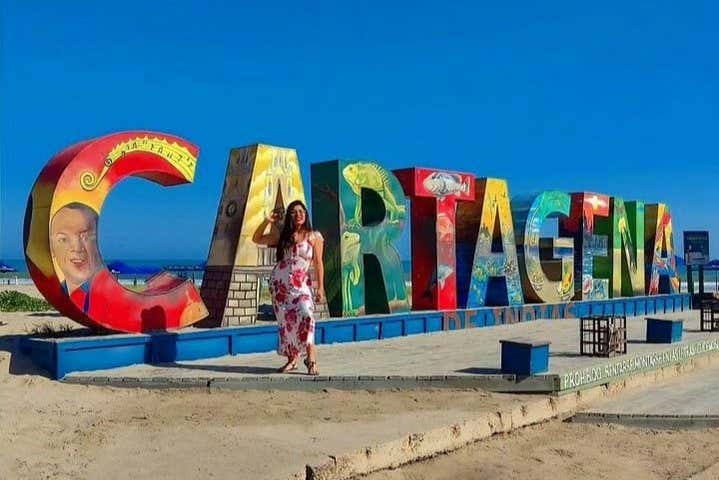 Uma mulher posando com as letras de Cartagena na praia