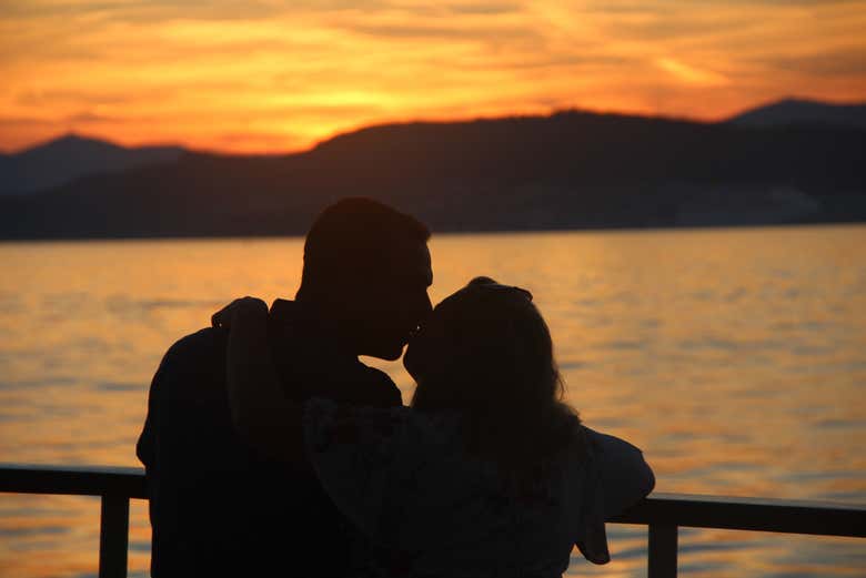 Casal apreciando o pôr do sol a bordo do barco