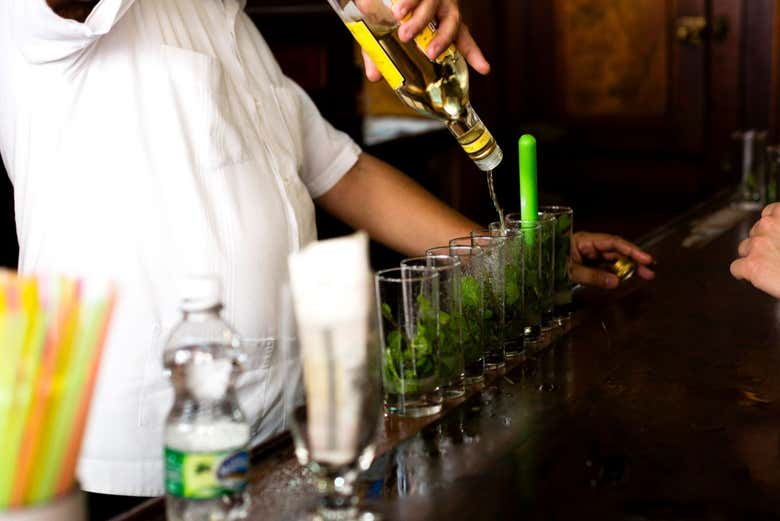 Un bartender vertiendo el ron en los cócteles