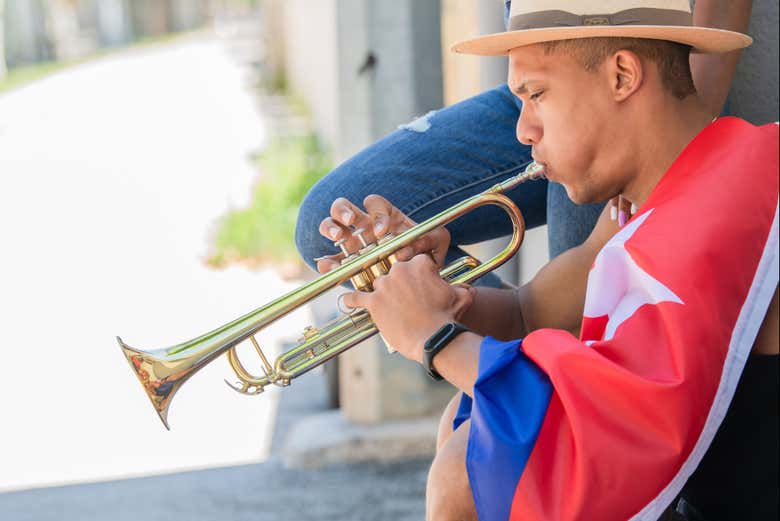 Un chico haciendo sonar una trompeta en las calles de La Habana