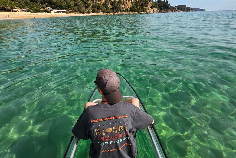 Un chico sentado en un kayak transparente