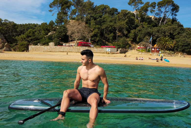Sentado en la tabla de paddle surf transparente