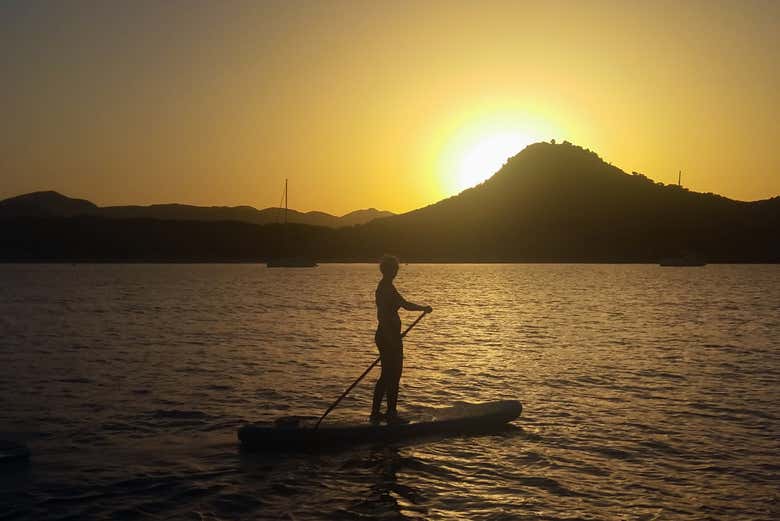 Una chica en una tabla de paddle surf al atardecer