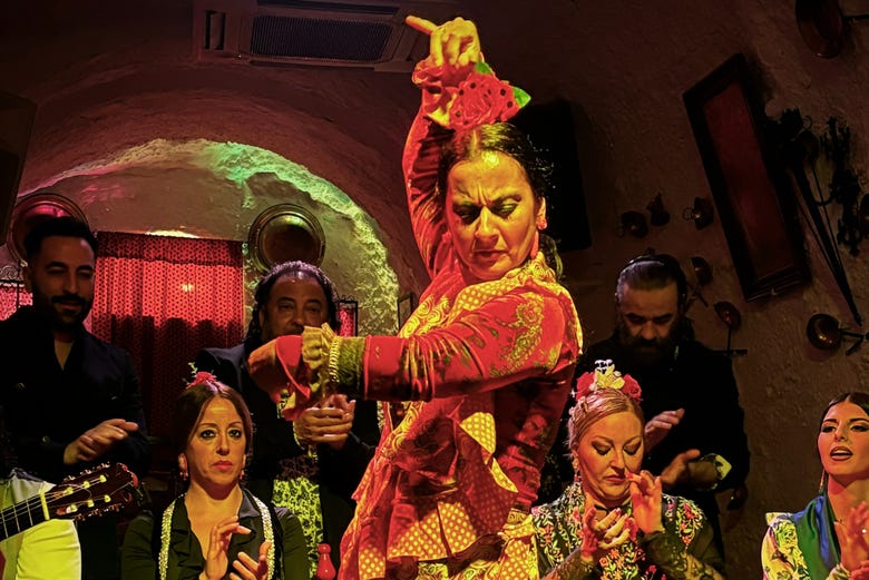 La bailaora danzando flamenco con el resto del elenco de fondo