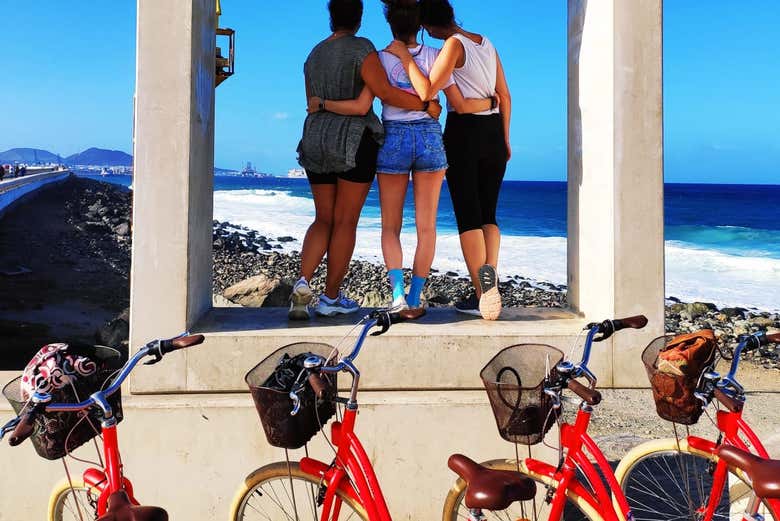Três amigas posando junto às bicicletas