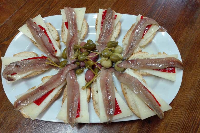 Ricas tapas de anchoas, pimiento rojo y queso sobre el pan