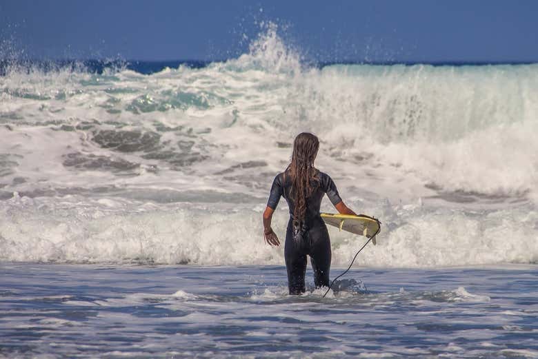 Uma aprendiz de surfista entrando na água