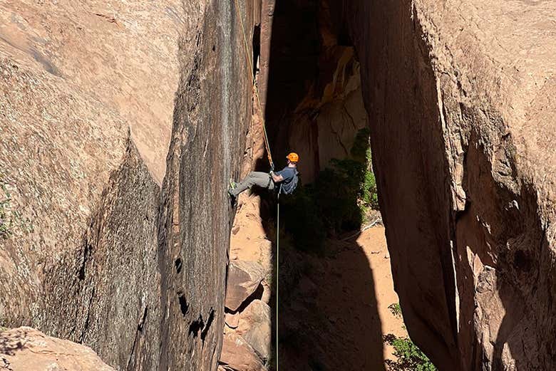 Um jovem praticando canyoning em uma parede do cânion