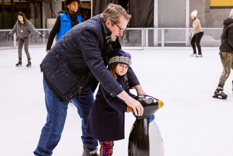 Um pai e sua filha patinando sobre o gelo