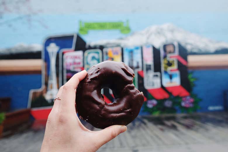 Un dónut de chocolate frente a un cartel de Seattle