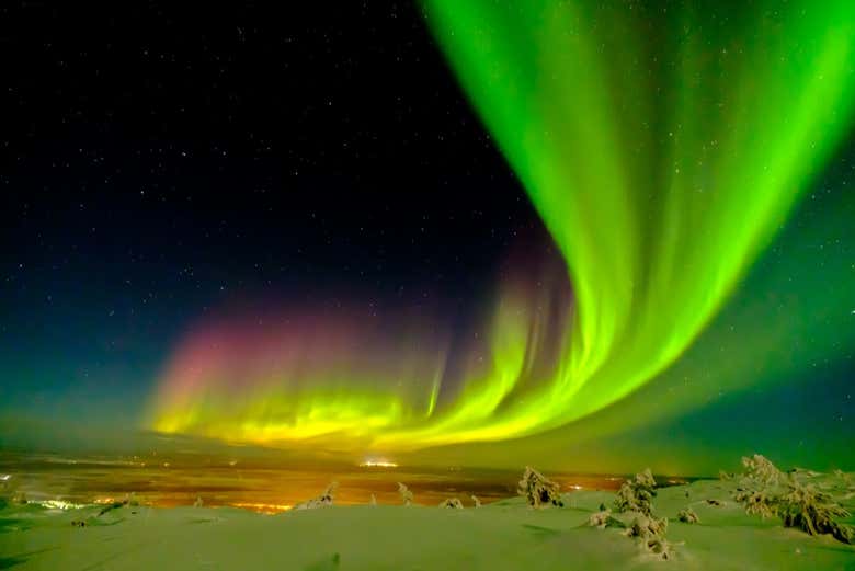 Vista noturna de Levi com a aurora boreal no horizonte