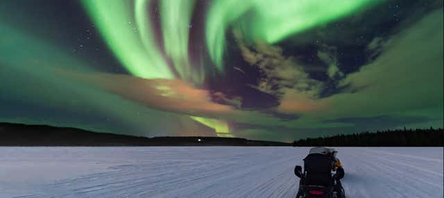 Passeio de moto de neve sob a aurora boreal