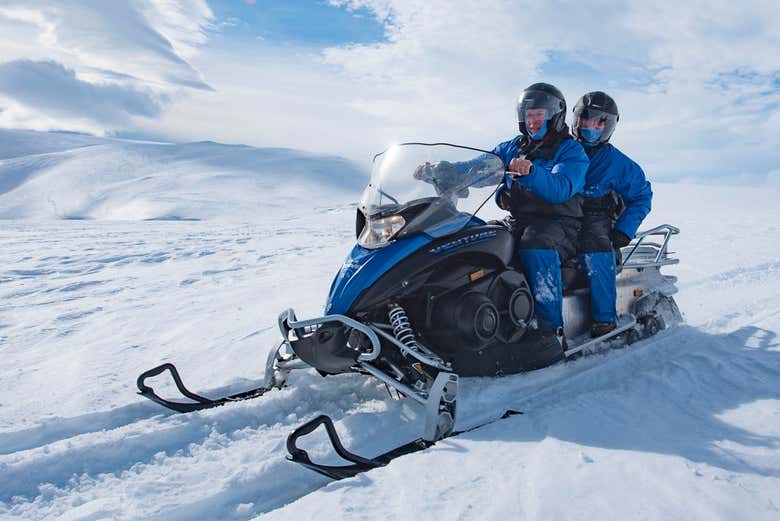 Pareja disfrutando del paseo en moto de nieve