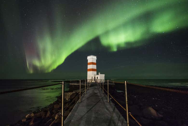 Aurora boreal sobre um farol islandês