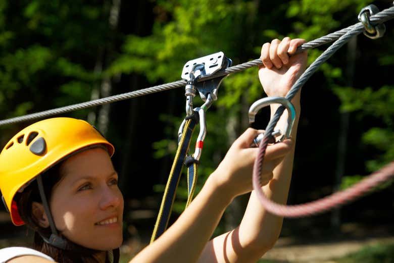 Uma mulher preparando o equipamento para a tirolesa