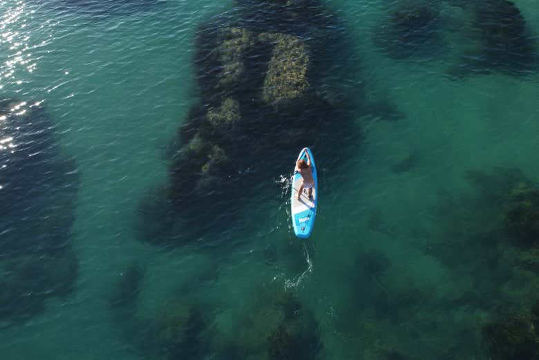 Vistas aéreas de una persona haciendo paddle surf en Cala Manbrù