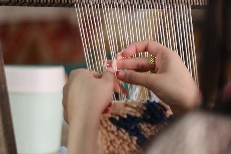 Atando con precisión los hilos que darán forma a la alfombra